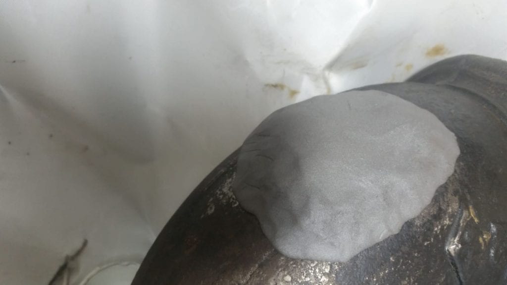 Steel epoxy putty used to seal a crack in a leaking cast iron wastewater pipe