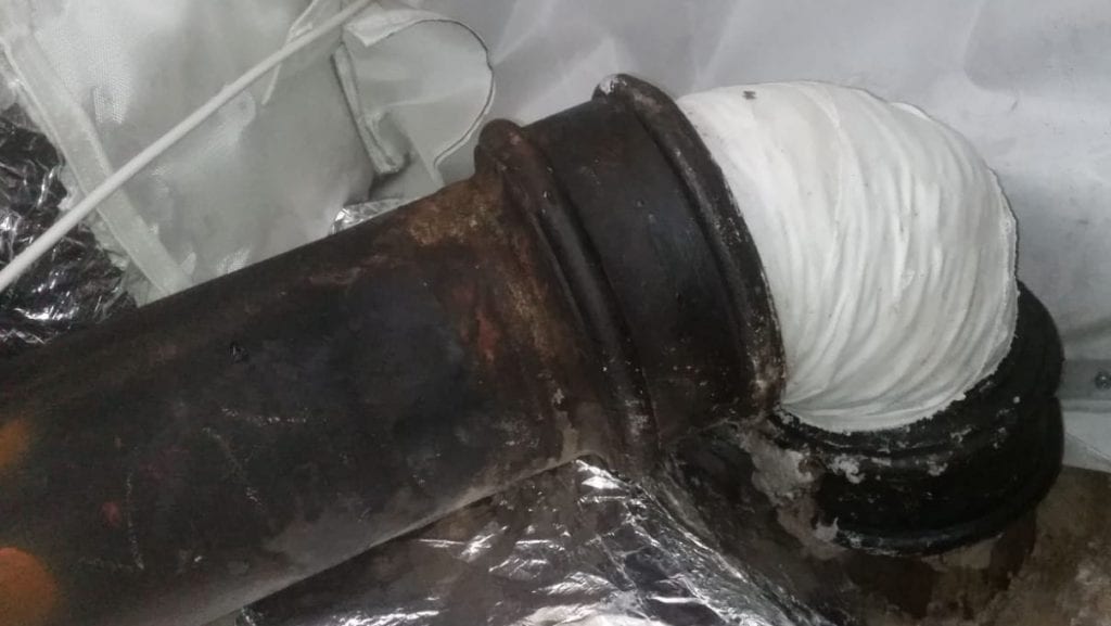 A SylWrap Pipe Repair Bandage applied over a cracked cast iron wastewater pipe in a London hotel